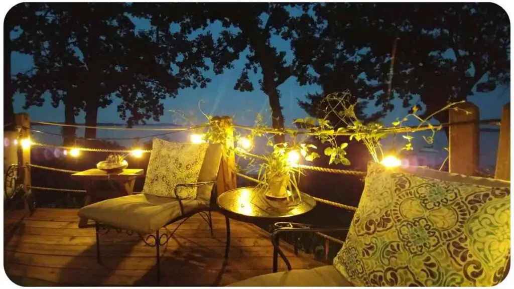 a deck with two chairs and a table lit up at night