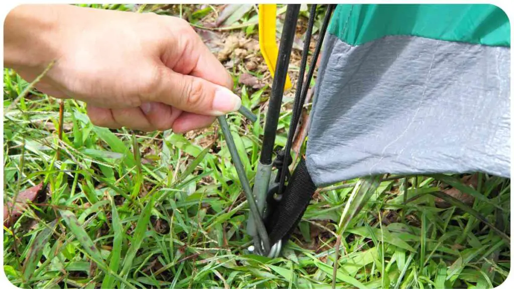 a person's hand holding onto a tent pole in the grass