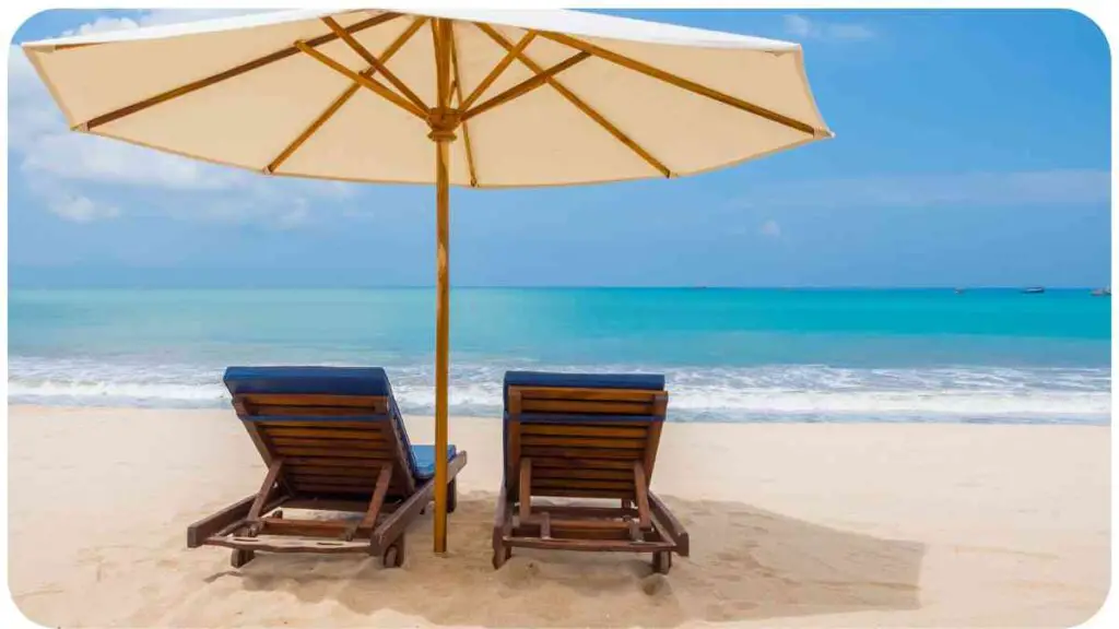 two lounge chairs under an umbrella on the beach