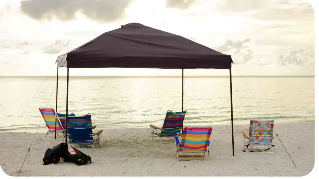 a tent on the beach with chairs and a dog