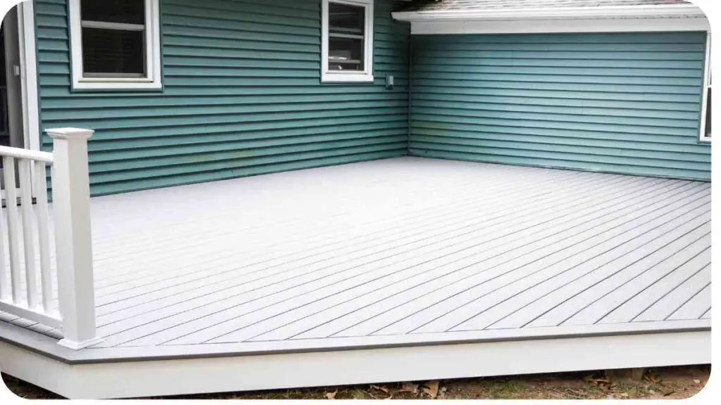 a deck with a white railing and blue siding