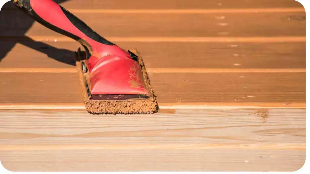 a person using a brush to clean a wooden deck