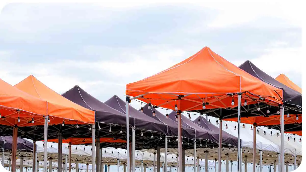 a row of orange and black tents on the beach