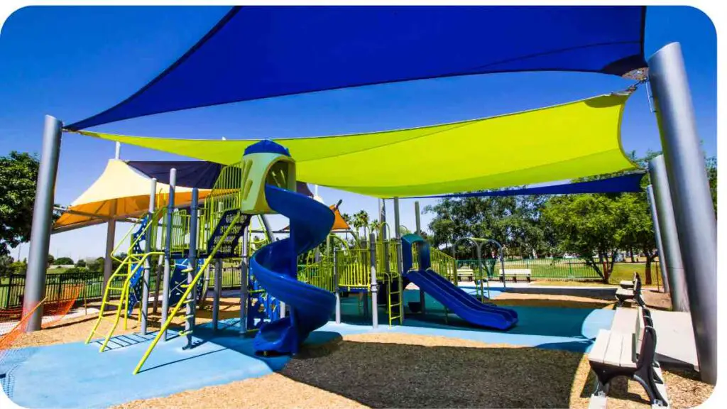 colorful playground equipment in a park with blue, yellow and green shade sails