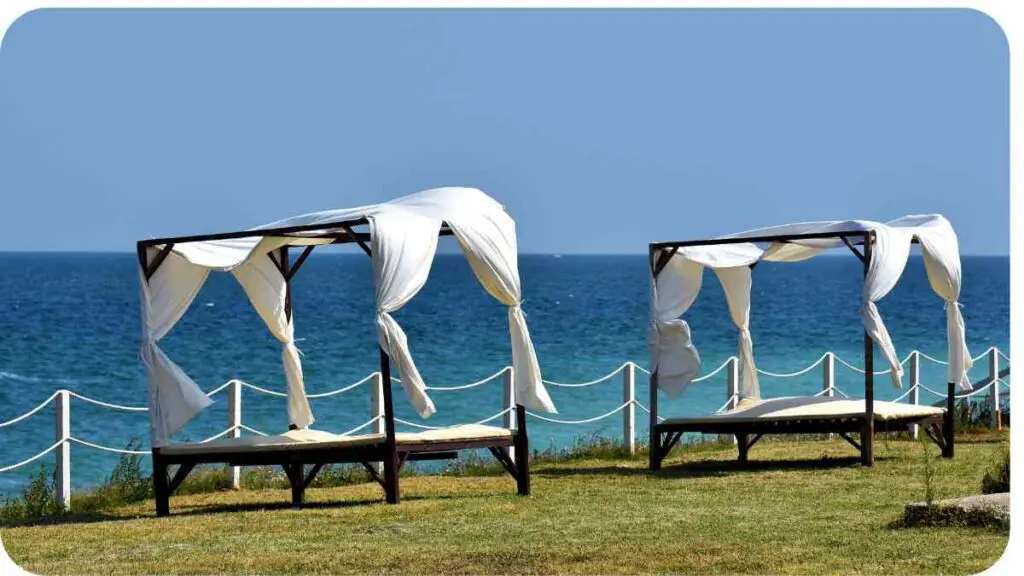 two canopy beds on the grass next to the ocean