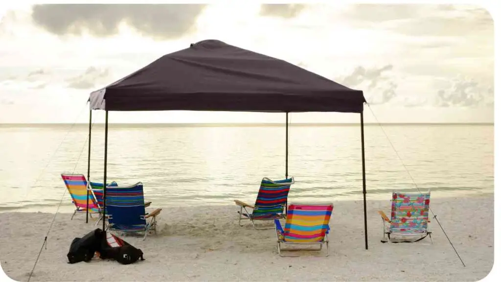 a tent on the beach with chairs and umbrellas