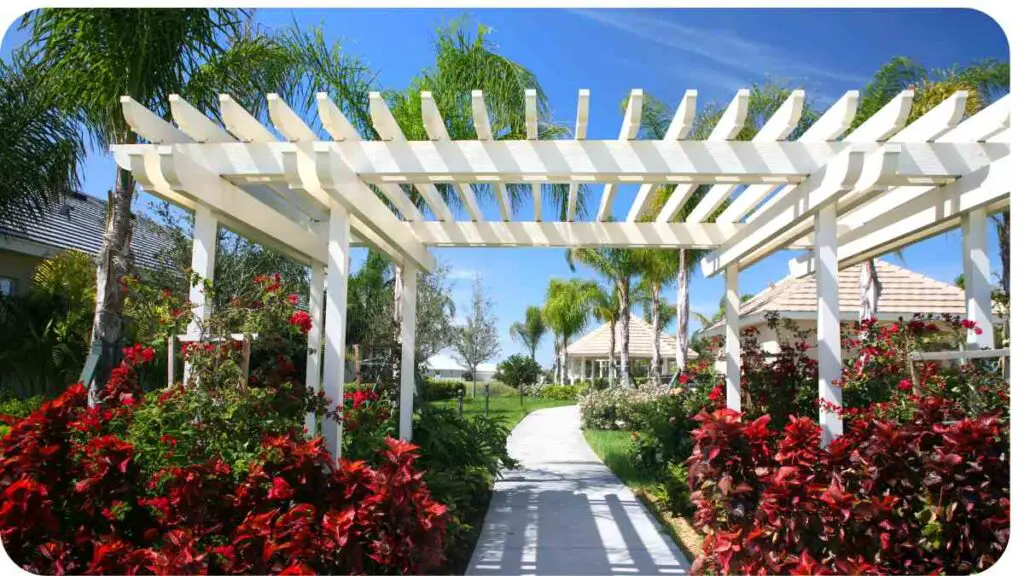 a pergola with red flowers in front of a house